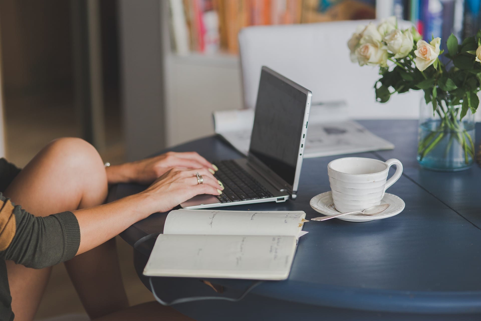 Estudiante de medicina estudiando desde casa con su laptop y cuaderno, en un ambiente tranquilo y organizado con café y flores, simbolizando el aprendizaje con propósito.