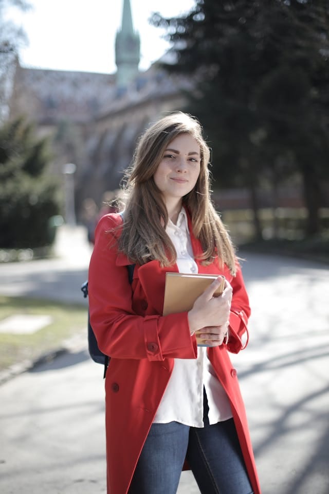 Estudiante de medicina con abrigo rojo sosteniendo un cuaderno, símbolo de estudio y dedicación académica.